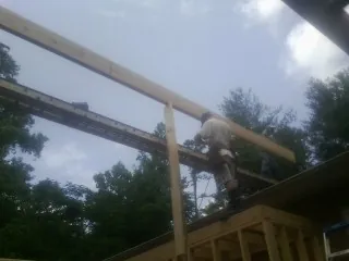 Carpenter setting a ridge beam over a new addition frame — Ice Dam Removal by Roofing Brothers in Leander